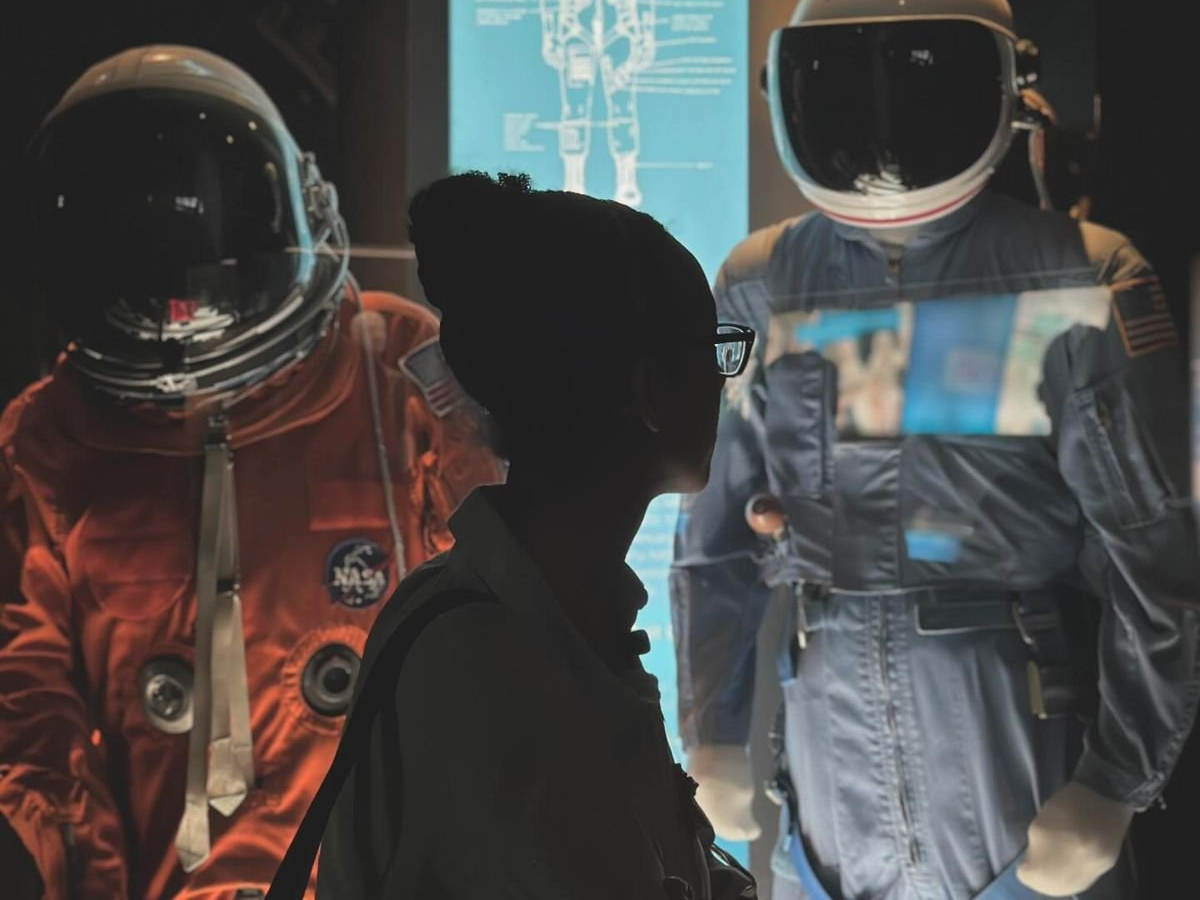 A visitor pausing before a spacesuit display, symbolising community as a shared mission of exploration